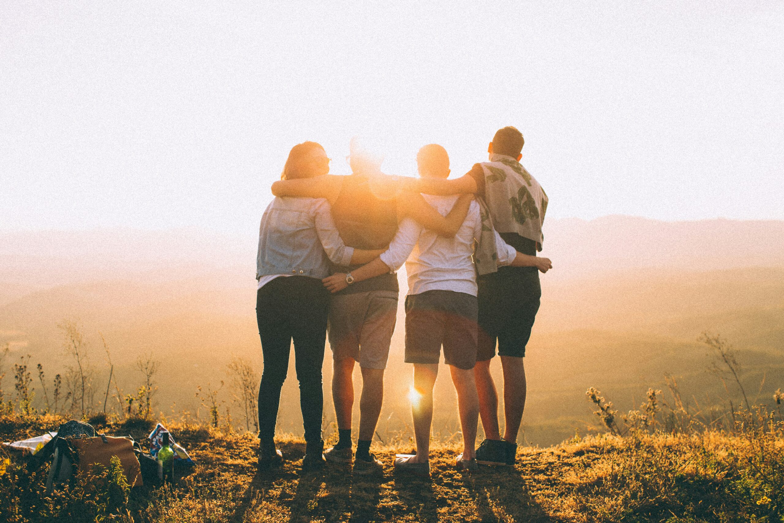 four adults embracing at sunset